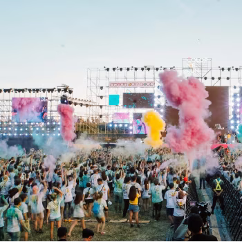 A festival with people standing in front of a stage.