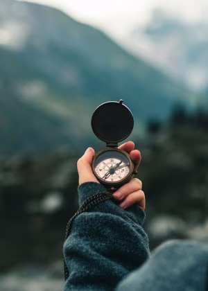 A hand holding a compass.