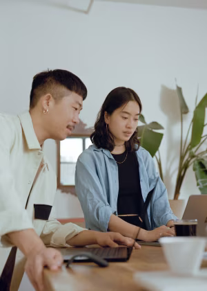 Two students working toegether on a laptop.